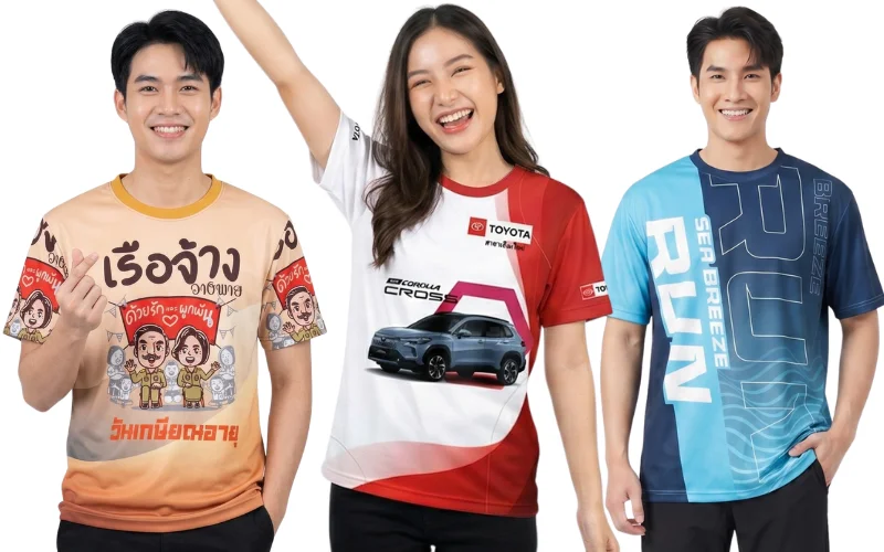 ตัวอย่างเสื้อพิมพ์ลายตามสั่งและเสื้อกิจกรรม 3 รูปแบบ ซ้าย: เสื้อที่ระลึกวันเกษียณอายุราชการครูพิมพ์ลายการ์ตูนล้อเลียน "เรือจ้างอาลัย ด้วยรักและผูกพัน" โทนสีน้ำตาลส้ม กลาง: เสื้อกิจกรรมโฆษณารถยนต์ TOYOTA COROLLA CROSS โทนสีขาวแดง ขวา: เสื้อวิ่งพิมพ์ลายกราฟิกสปอร์ตสลับสีฟ้ากรมท่าพิมพ์คำว่า "RUN SEA BREEZE" แสดงงานพิมพ์ระบบซับลิเมชันคุณภาพสูงจากโรงงาน