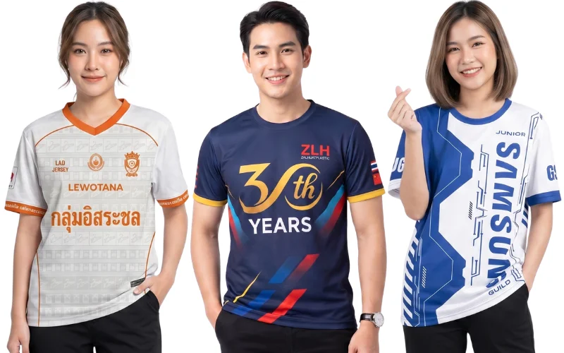 ตัวอย่างเสื้อพิมพ์ลายสั่งทำและเสื้อกิจกรรมองค์กร 3 รูปแบบ ซ้าย: เสื้อคอวีพิมพ์ลายสีขาวส้ม "กลุ่มอิสระชล" ดีไซน์คลาสสิก กลาง: เสื้อยืดพิมพ์ลายครบรอบบริษัท "ZLH 30th YEARS" โทนสีกรมท่าตัดทองและแดง ขวา: เสื้อทีมพิมพ์ลายกราฟิกแนวสปอร์ตสีน้ำเงินขาว "SAMSUNG GUILD" แสดงงานพิมพ์ระบบซับลิเมชัน (Sublimation) คุณภาพสูงจากโรงงาน