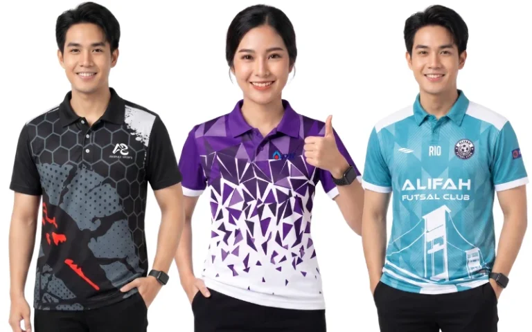 ตัวอย่างงานจากโรงงานรับผลิตเสื้อพิมพ์ลาย แสดงแบบเสื้อโปโลสปอร์ตและเสื้อกีฬาพิมพ์ลาย 3 ดีไซน์ ด้านซ้ายเป็นผู้ชายสวมเสื้อคอปกโทนสีดำเทาลายรังผึ้งตัดกราฟิกสีส้มแดงและสีขาว ตรงกลางเป็นผู้หญิงสวมเสื้อทีมคอปกสีม่วงขาวพิมพ์ลายเรขาคณิตสามเหลี่ยมเฉดสีสดใสพร้อมยกนิ้วโป้ง และด้านขวาเป็นผู้ชายสวมเสื้อกีฬาคอปกสีฟ้าเทอร์ควอยซ์พิมพ์ลายทีมฟุตซอล ALIFAH FUTSAL CLUB ผลิตจากเนื้อผ้ากีฬาเกรดพรีเมียม